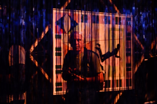 A stylish portrait of an actor in a dramatic pose against a colorful, modern backdrop.