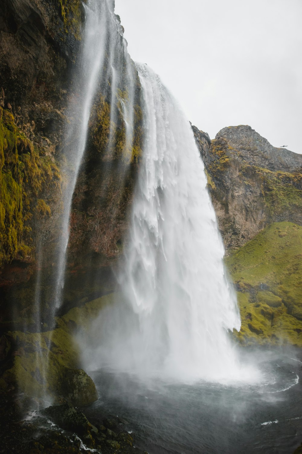 a waterfall with green grass and rocks