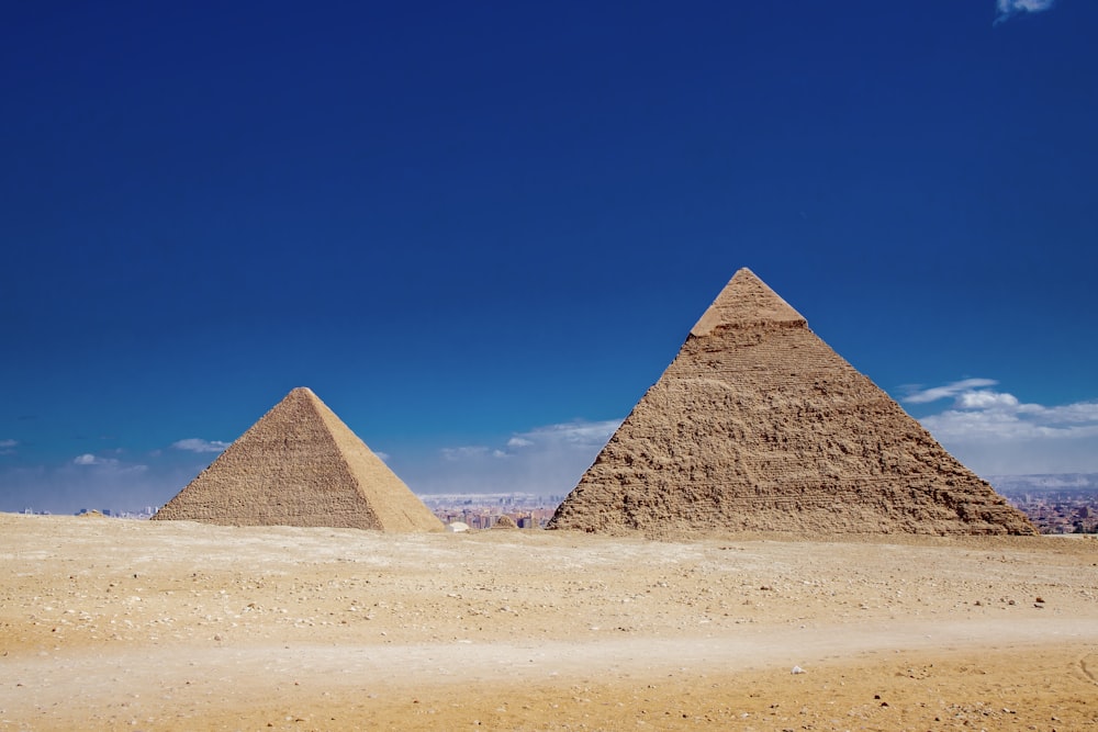 a couple of pyramids in a desert with Giza pyramid complex in the background