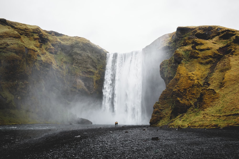 a person standing on a rocky cliff with a waterfall