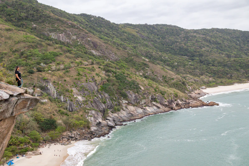 Morros verdes e praia de água turquesa vistos da trilha