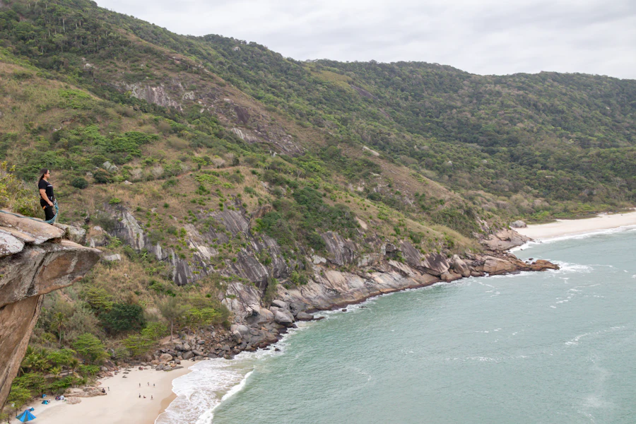 Morros verdes descendo até uma praia de água turquesa