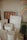 A variety of art supplies and decorative objects are neatly arranged. There are white sculptural elements resembling columns, a framed piece with vertical stripes, and sheets of paper with sketched lines. The background features a colorful, striped abstract painting.