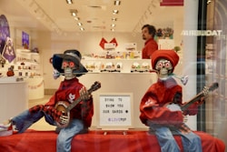 a couple of people in clothing holding guitars in a store