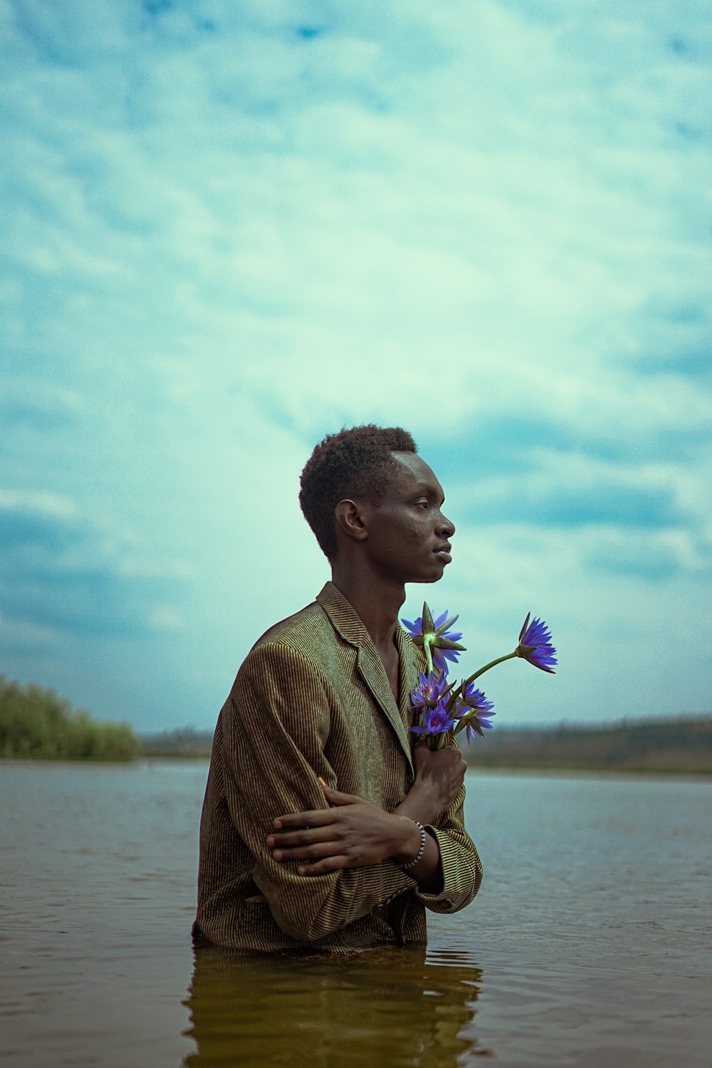 a man holding flowers in a body of water