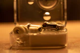 A pair of modern wireless earbuds resting inside their compact charging case, glowing softly.