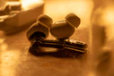 Modern wireless earbuds resting on a minimalist white surface with subtle gold reflections