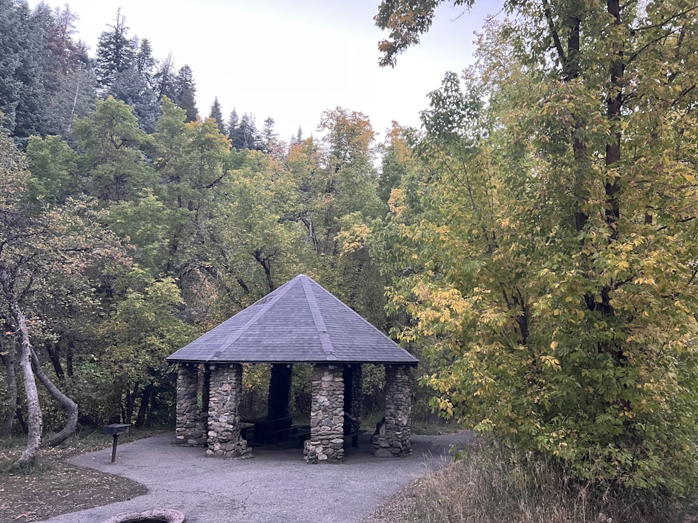 a stone building with a roof surrounded by trees