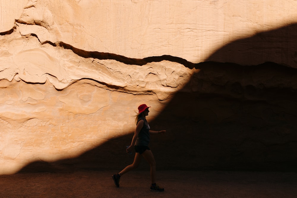 a person walking in front of a rock wall