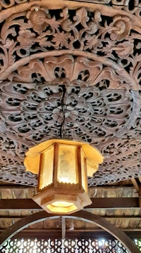 Close-up of a custom wooden lamp with intricate carvings and warm lighting.