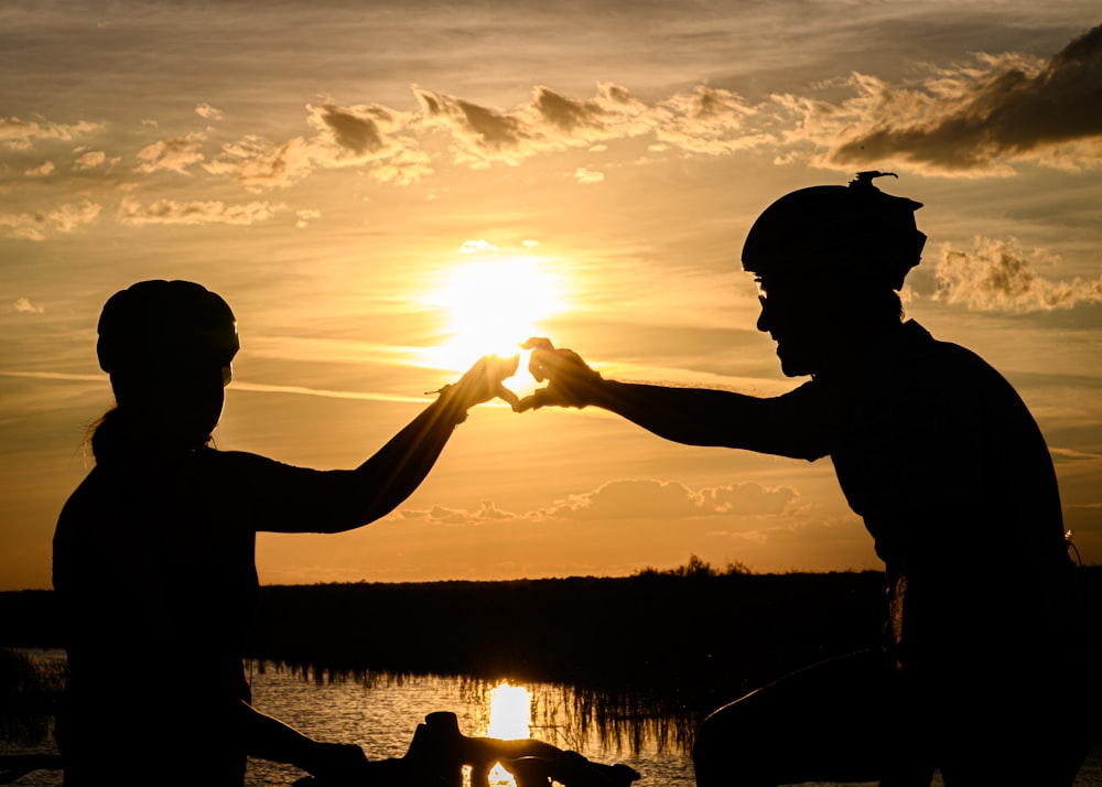 a man and woman holding hands and looking at the sunset
