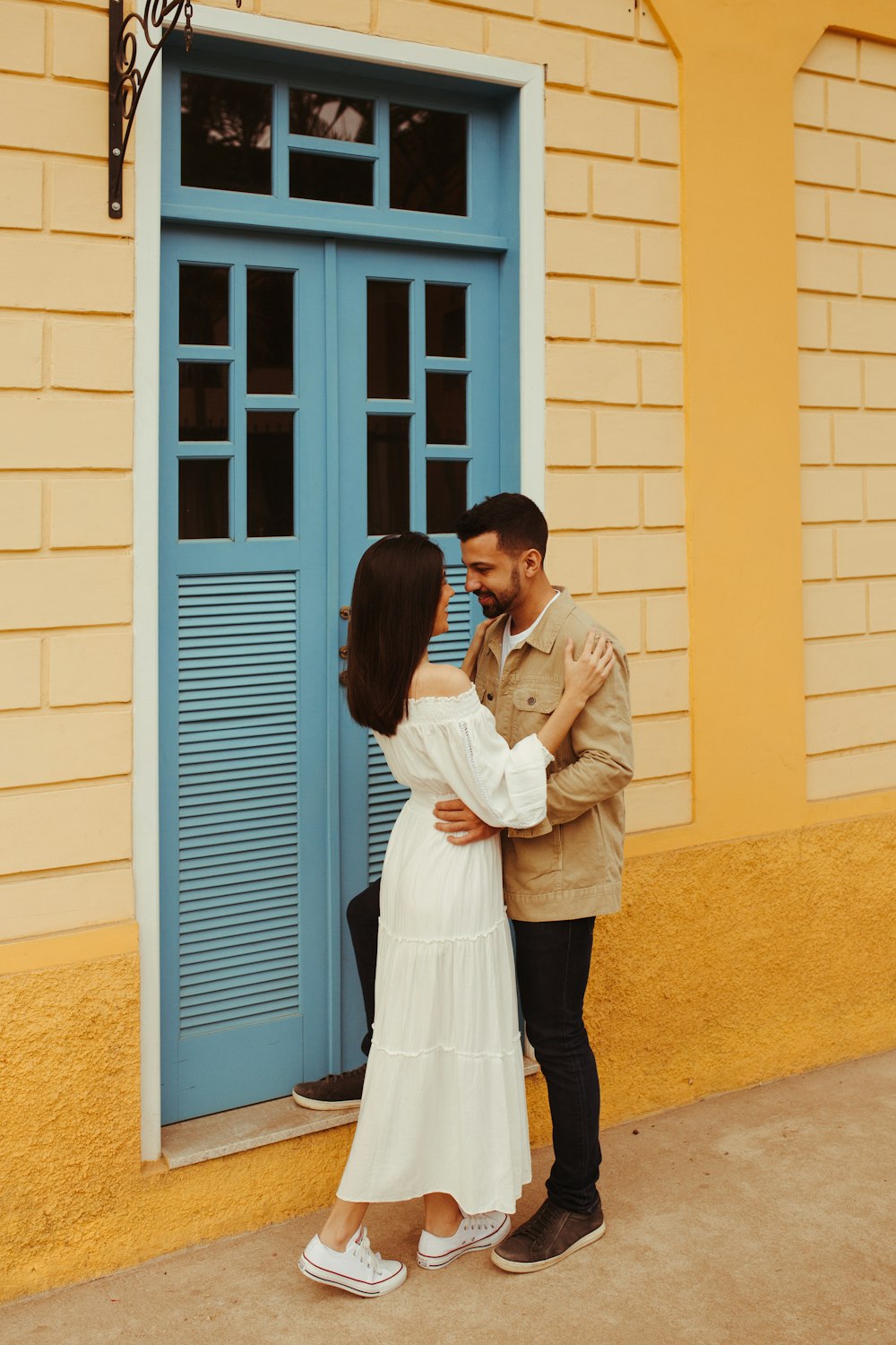 um homem e uma mulher se beijando na frente de uma porta azul