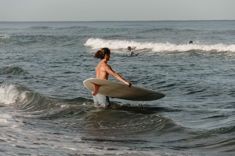 a person carrying a surfboard in the ocean