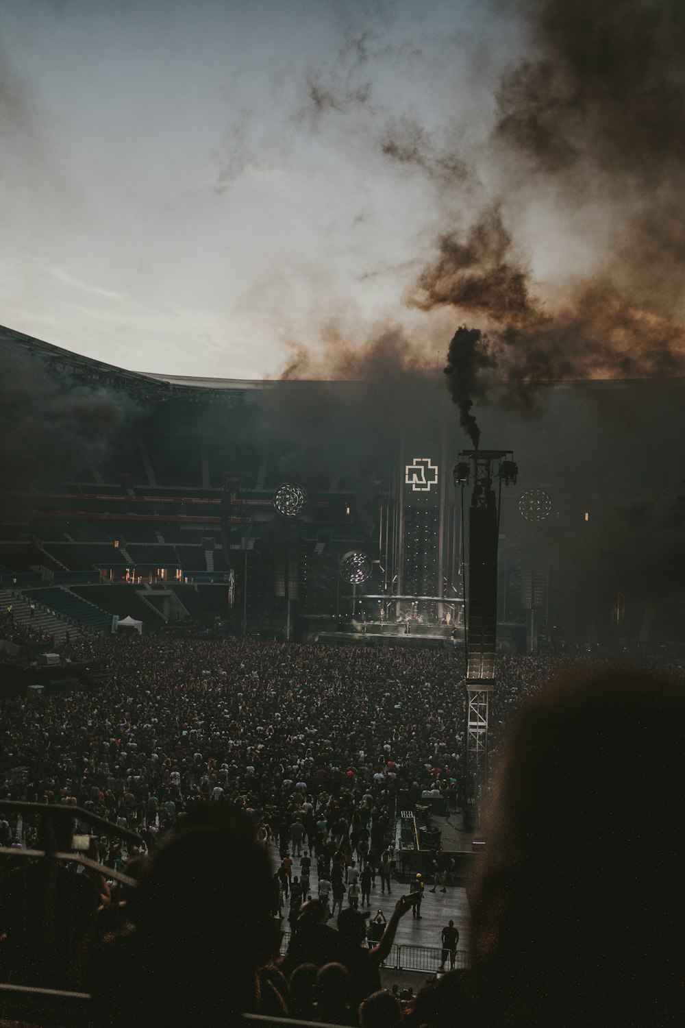a large crowd of people watching a stage with a large black smoke cloud