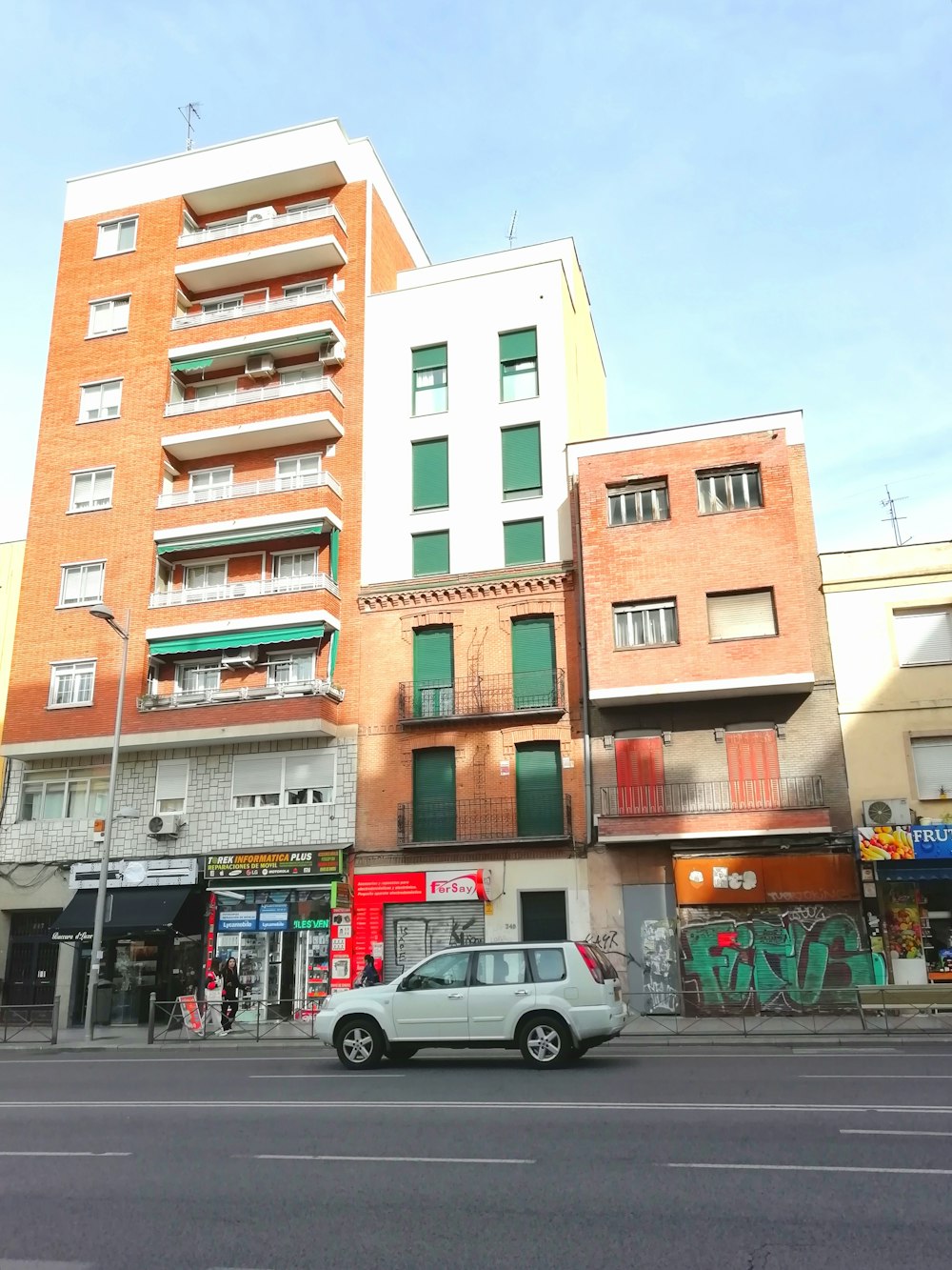 a car parked in front of a building with many balconies