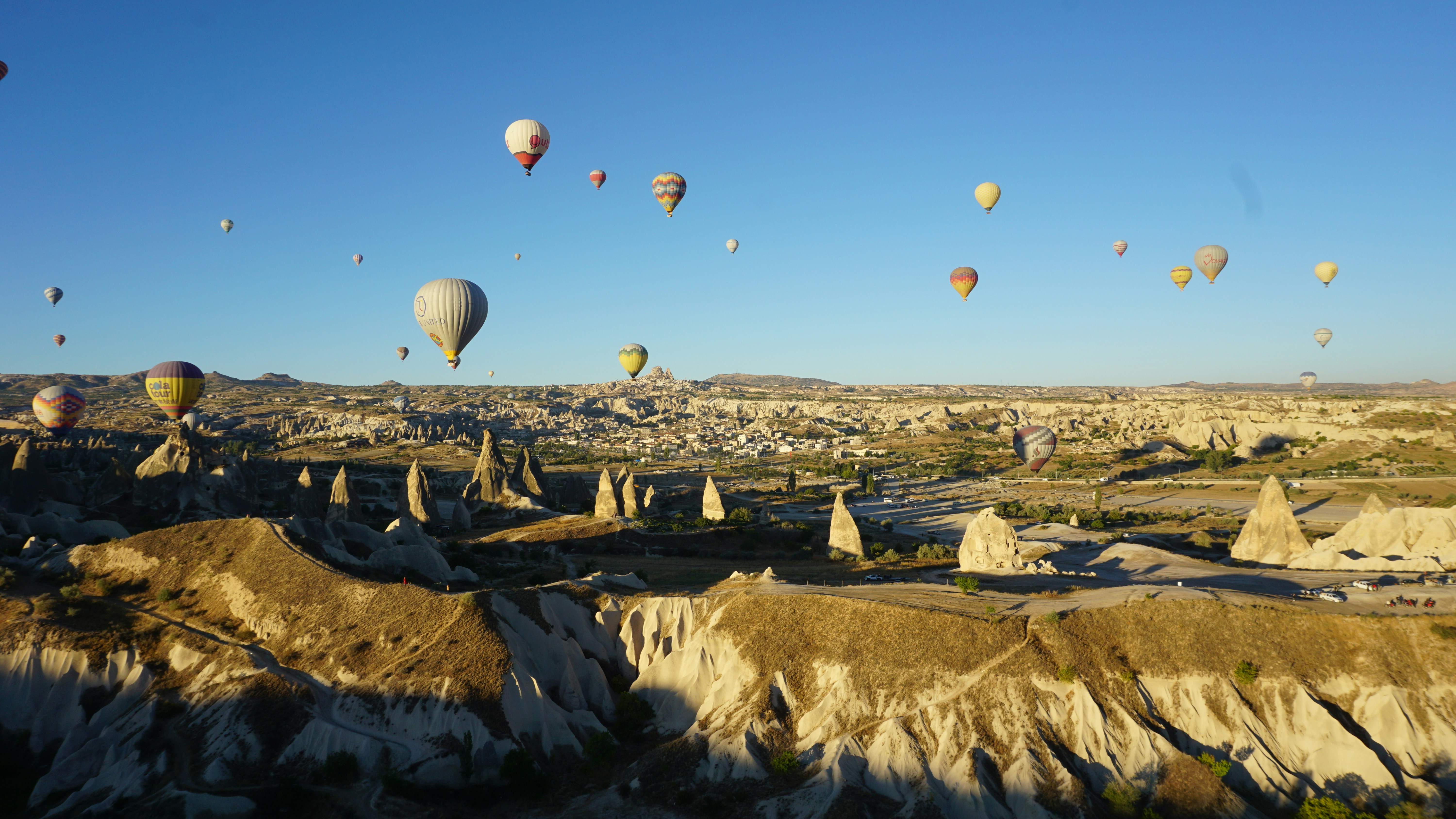 sekelompok balon udara di langit dengan Cappadocia di latar belakang