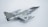 A model aircraft with a sleek, metallic design, featuring jet engines and distinctive military markings. The aircraft has dual wings and pointed nose with noticeable detail in its construction. The backdrop is a plain, light-colored surface that highlights the aircraft's shiny surface.