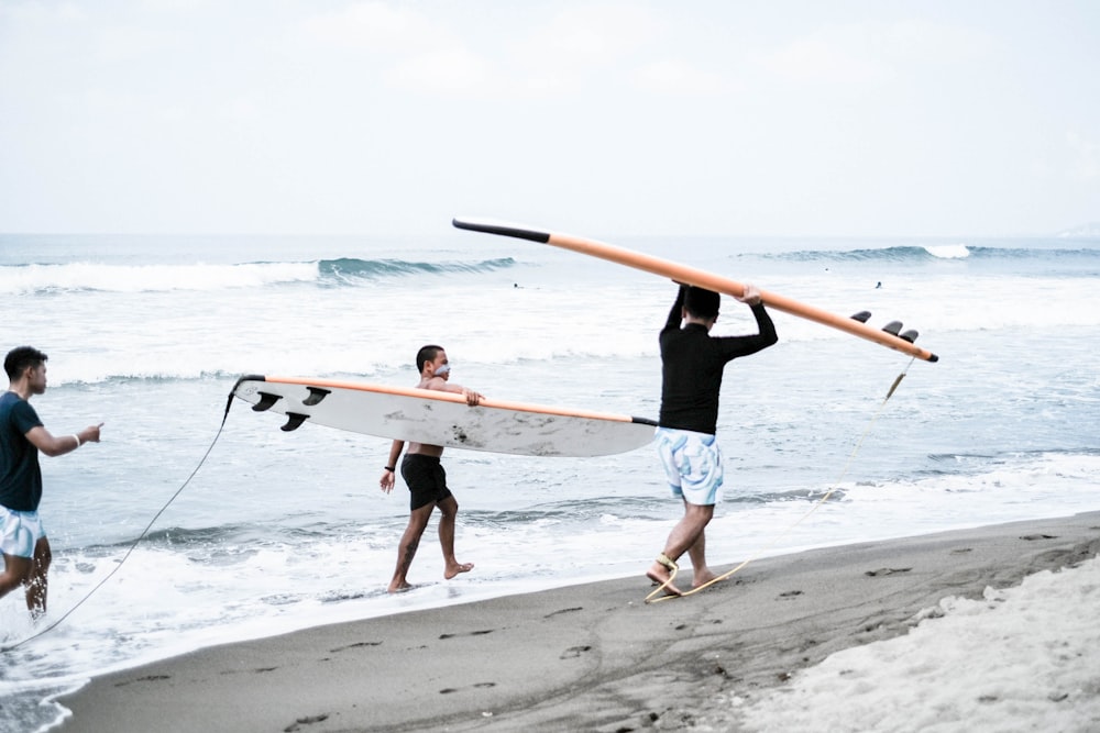 a group of people carrying surfboards on a beach