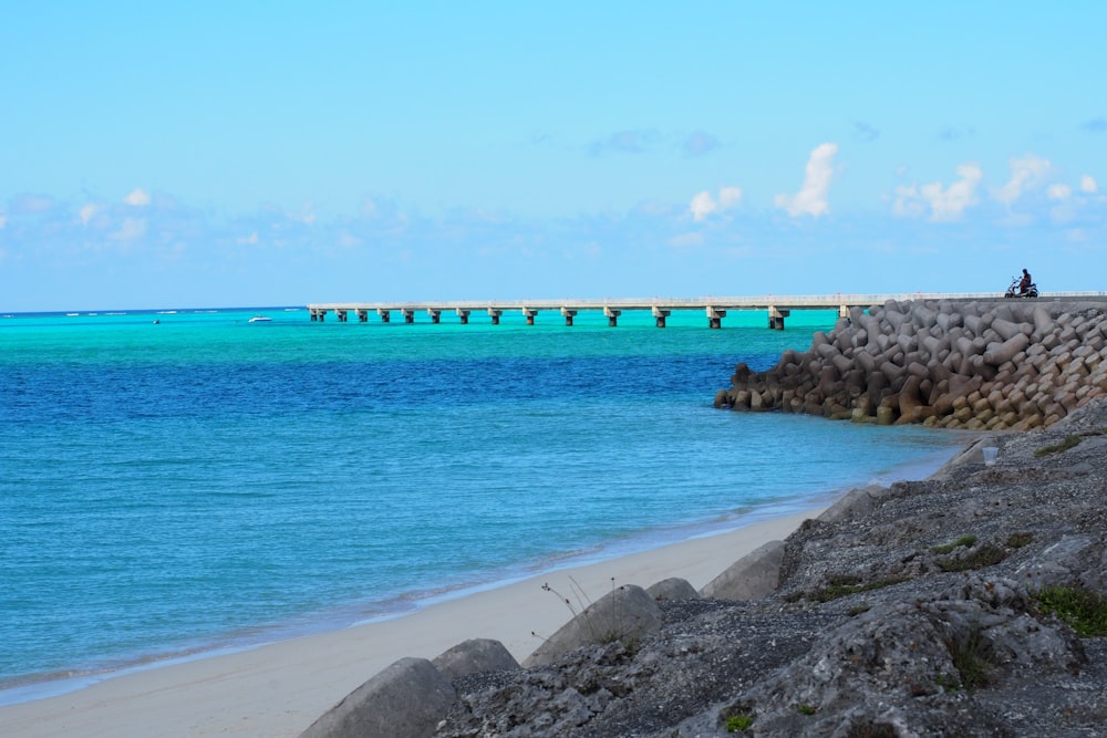 a beach with rocks and a pier