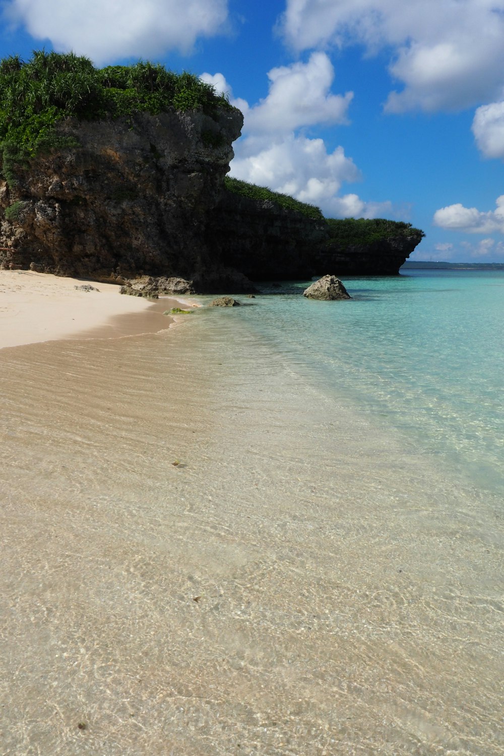 uma praia de areia com uma formação rochosa