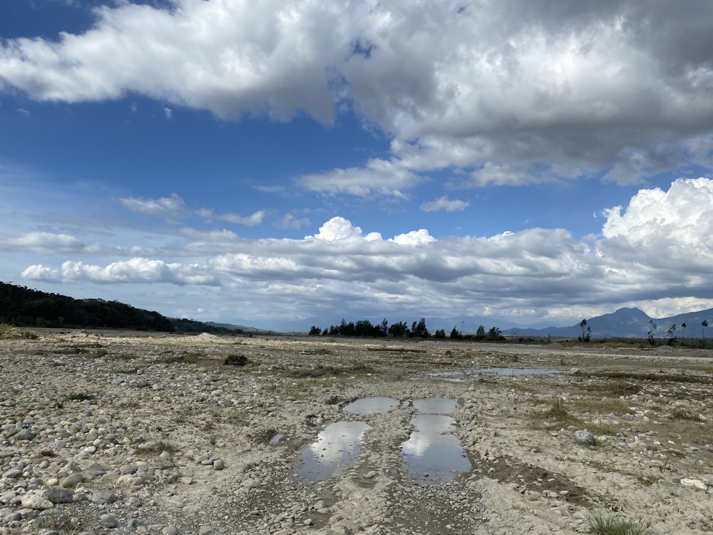 a landscape with a puddle and mountains in the background