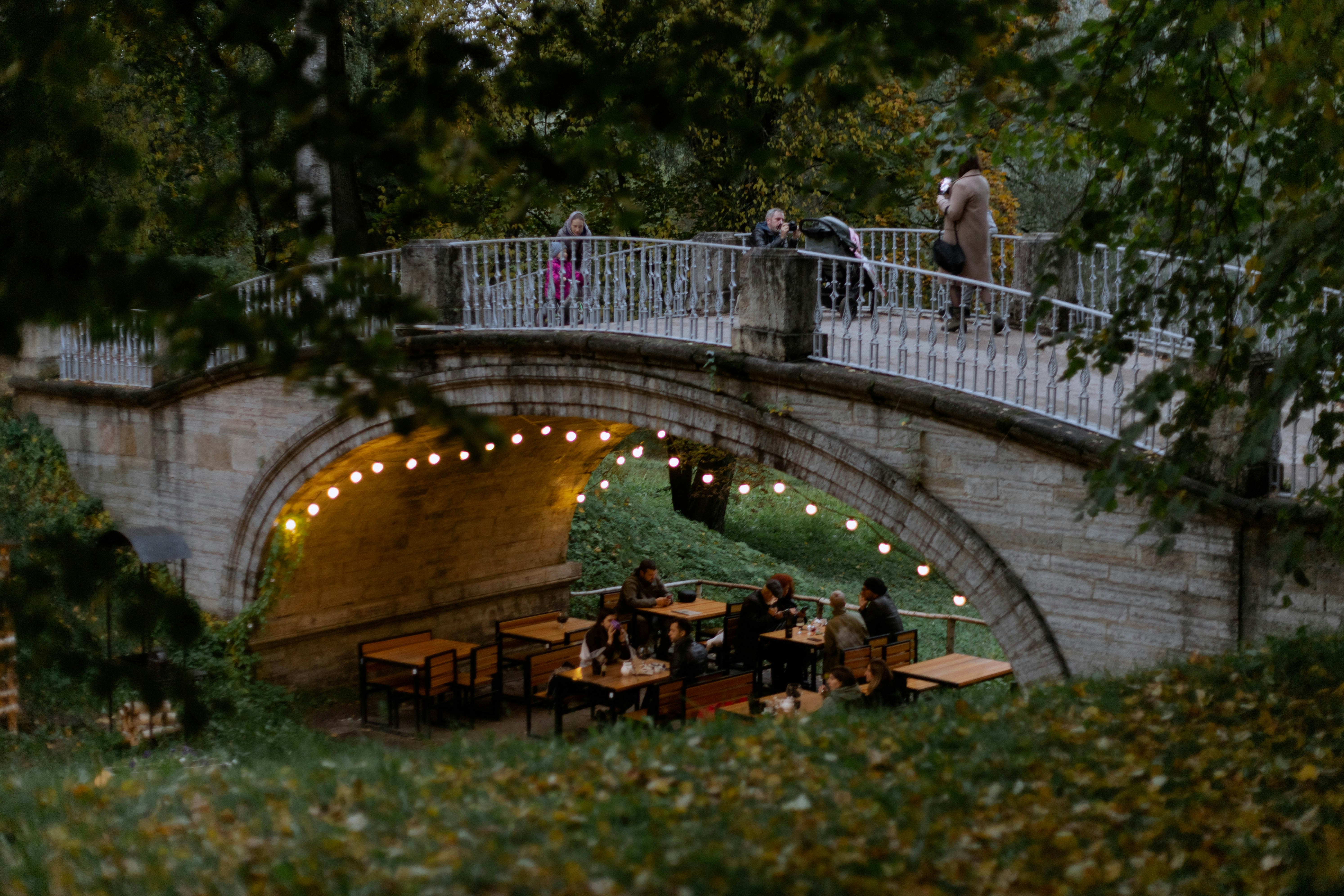 a group of people sitting on a bridge over a river