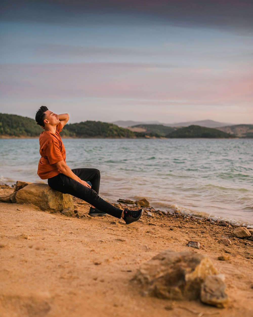 a man sitting on a rock by the water