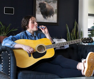 a person sitting on a couch playing a guitar