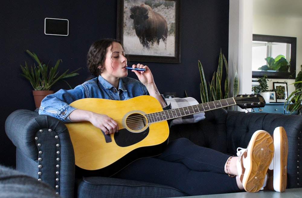 a person sitting on a couch playing a guitar