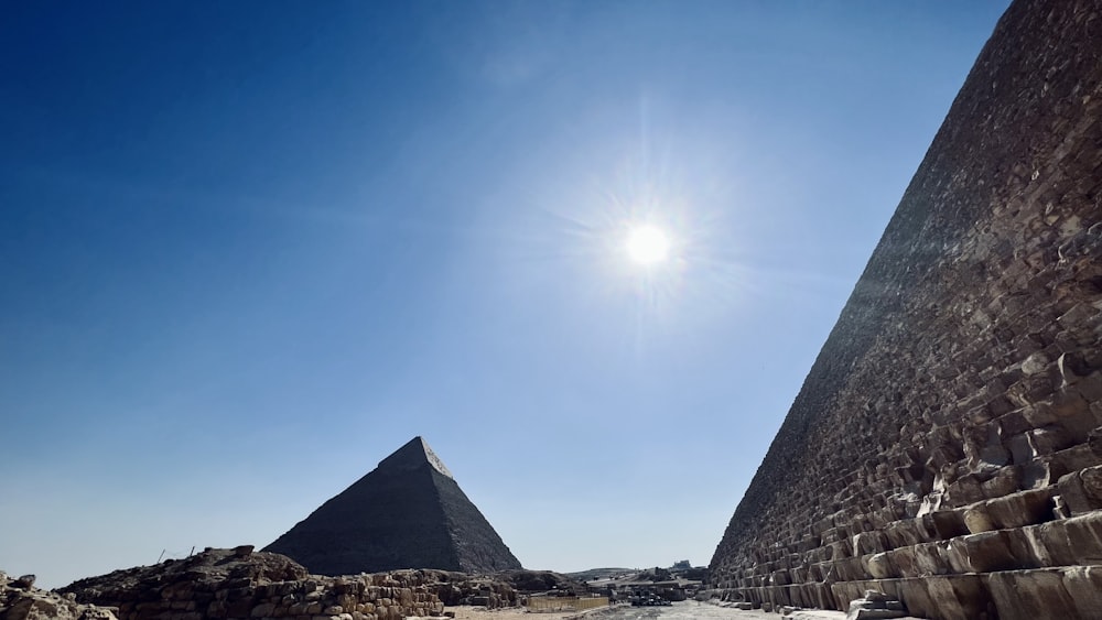 a group of pyramids with the sun in the background