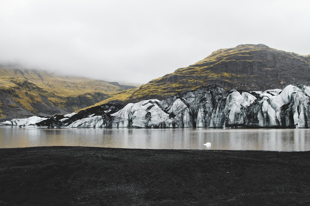 a body of water with snow covered mountains in the background