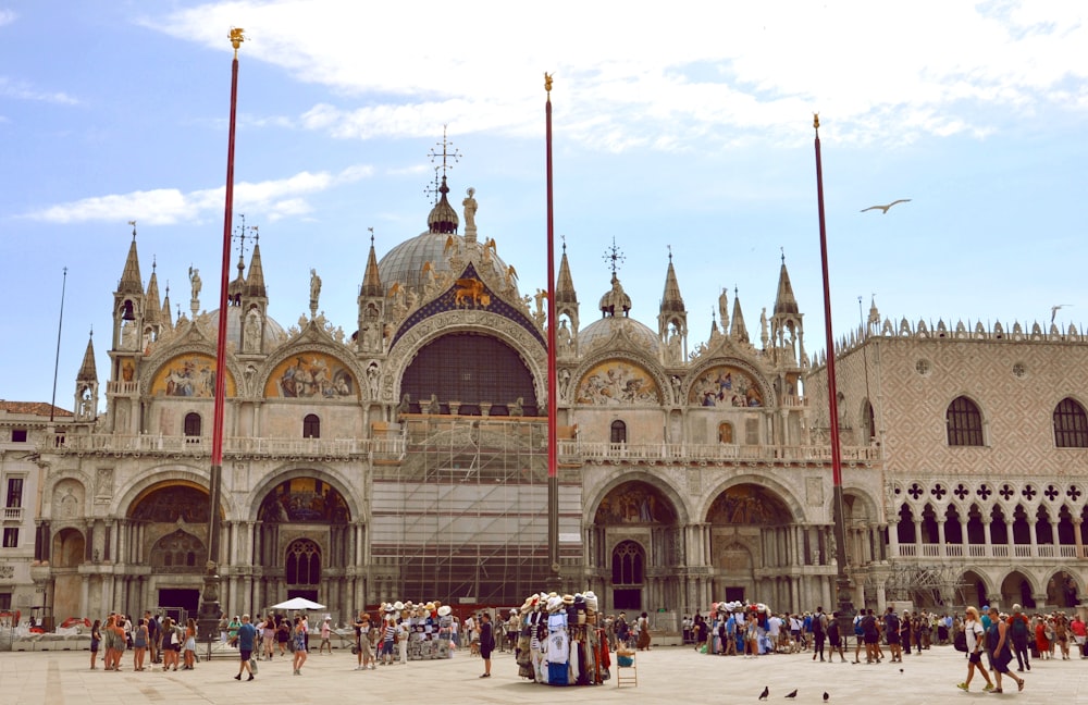 a large building with a crowd of people in front of it with St Mark's Basilica in the background