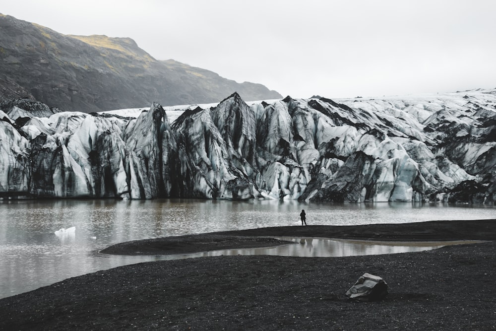 a person standing on a dock in front of a large glacier