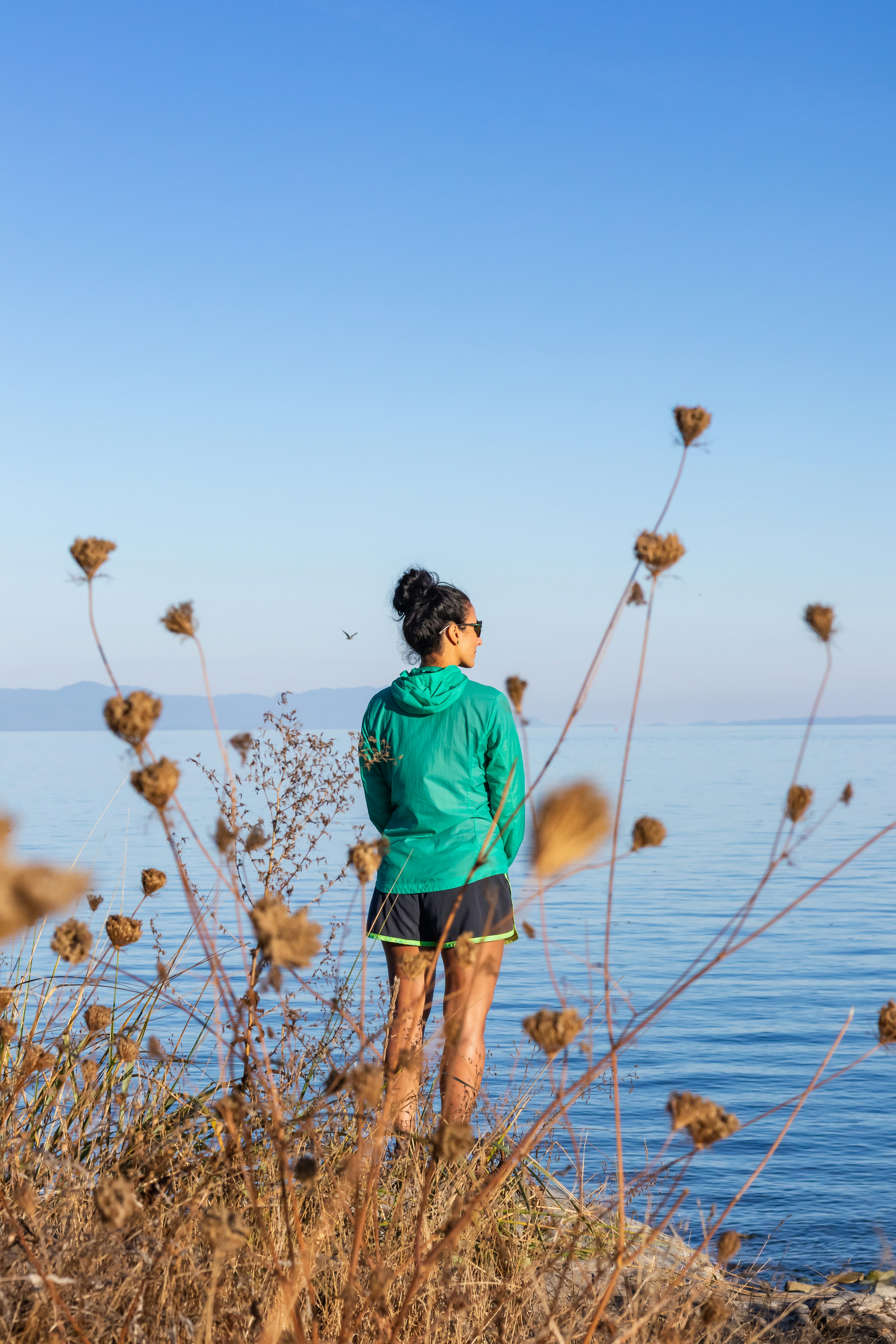 um homem de pé em um campo de grama alta com um corpo de água no fundo