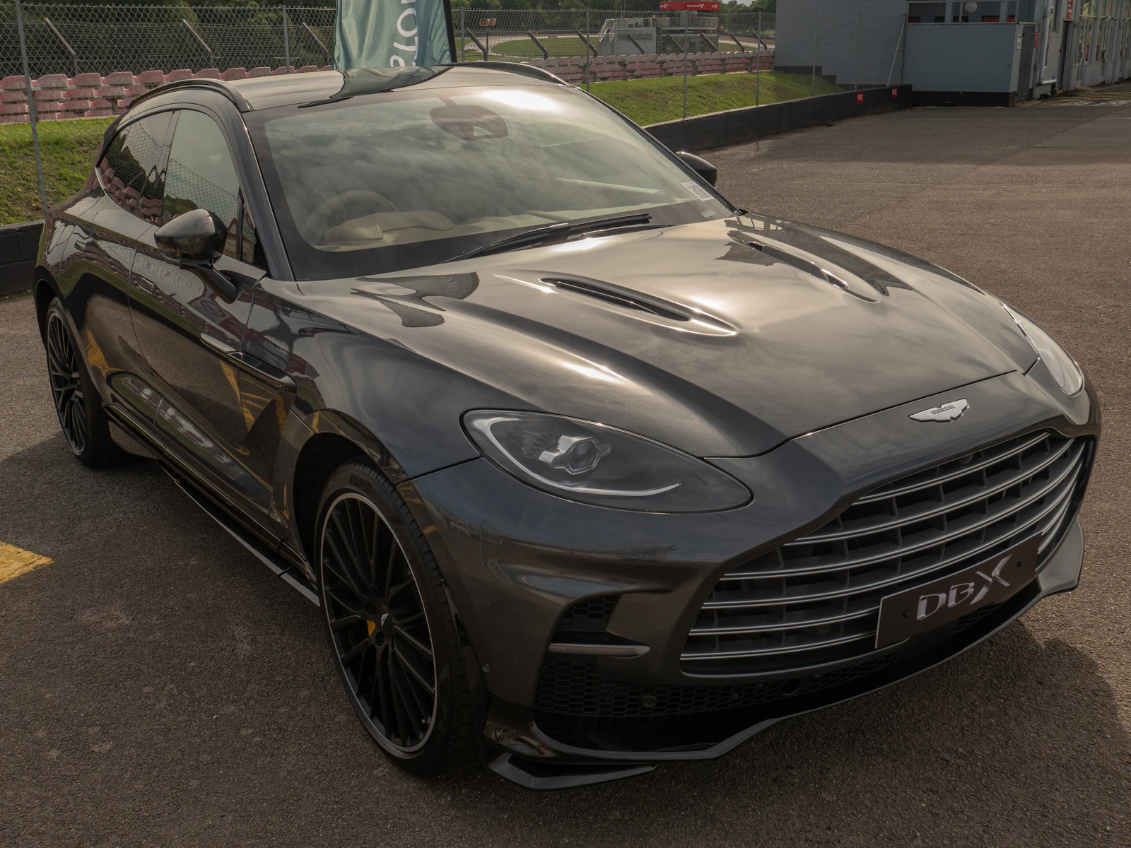 Dark gray Aston Martin DBX SUV parked at a racetrack