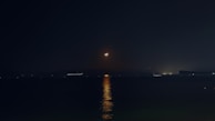 A serene photograph of gentle moonlight reflecting on a calm water surface at dusk.
