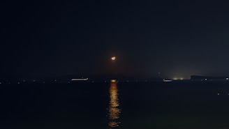 A serene photograph of gentle moonlight reflecting on a calm water surface at dusk.
