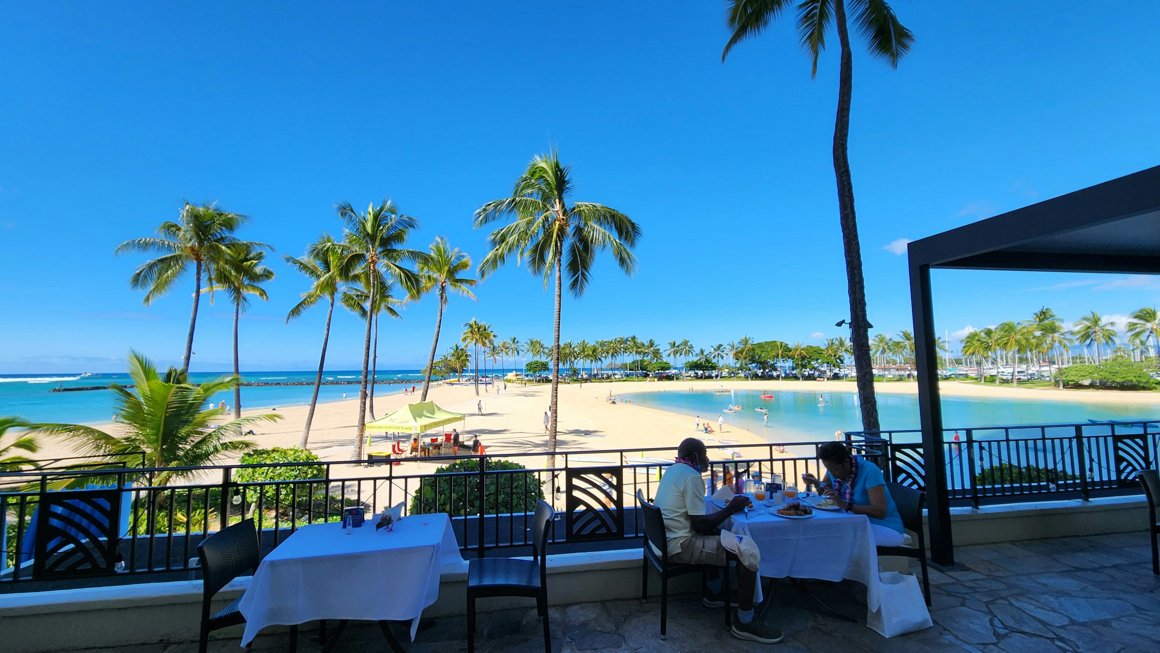 a couple of people sitting at a table on a deck overlooking a beach