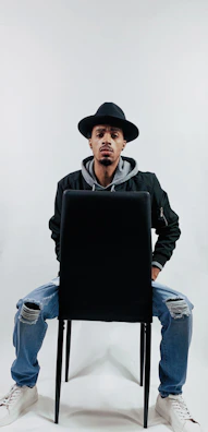 Man posing in a minimalist studio wearing a premium black hoodie paired with casual jeans.