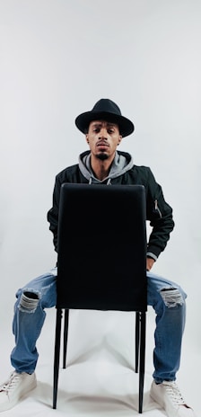 A sleek black jacket styled with jeans, photographed in a minimalist studio.
