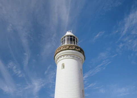 A modern lighthouse standing tall against a clear blue sky.