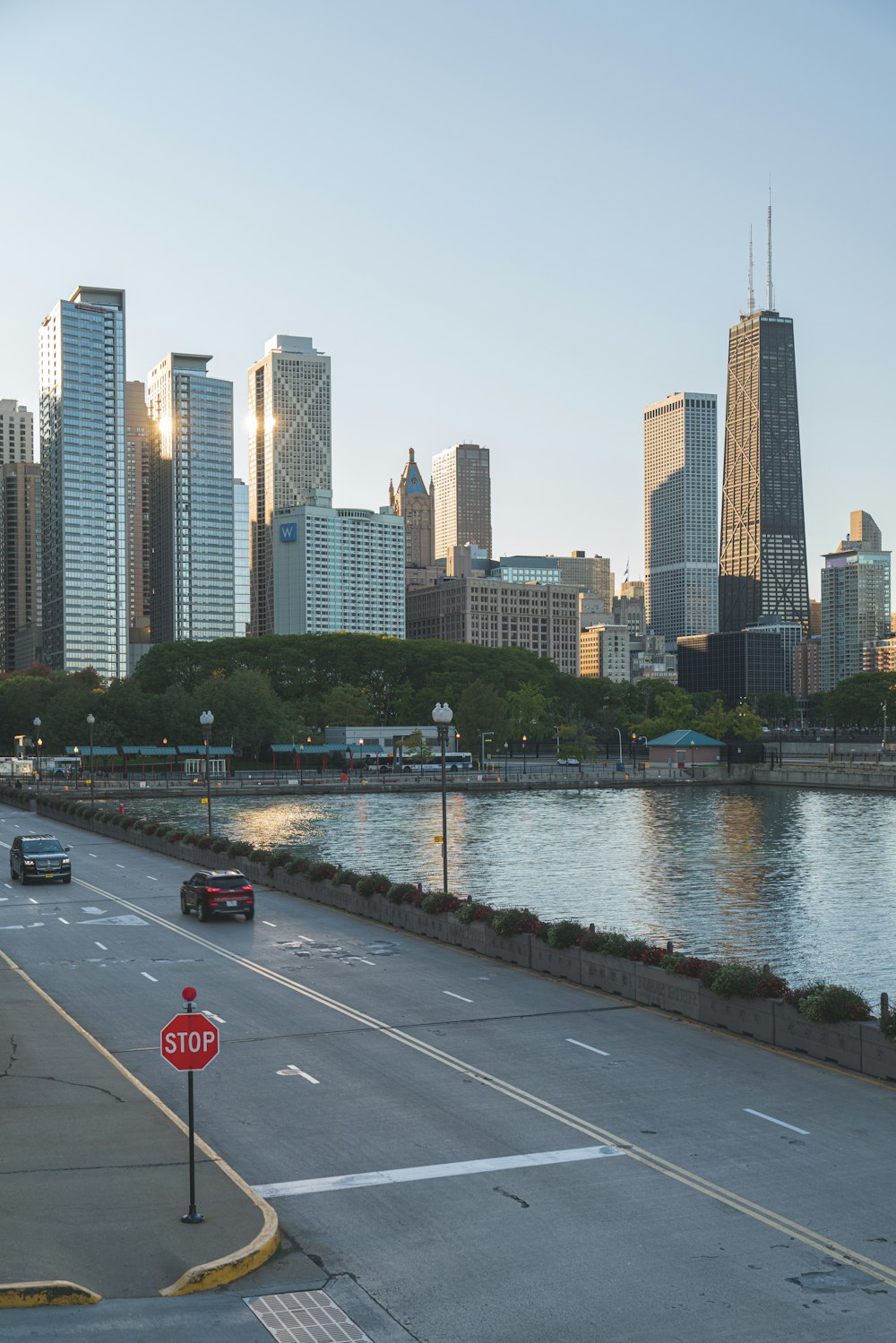 a road with cars on it by a body of water with a city in the background