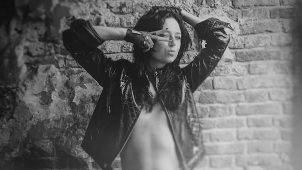 Monochrome photo of a model wearing a sleek jacket embossed with a stylized phoenix emblem.