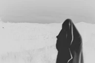 Black-and-white still of the protagonist silhouetted against a foggy, blood-red horizon.