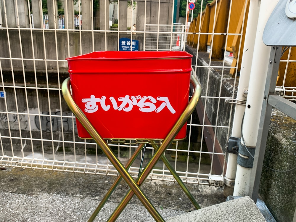 a red bucket on a metal fence