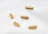 Five brown capsules are scattered on a soft, white fabric surface. The capsules are evenly spaced and slightly glossy, giving them a smooth appearance.