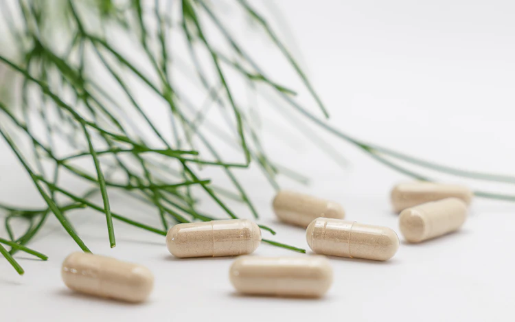 A group of white supplement capsules on a plain surface
