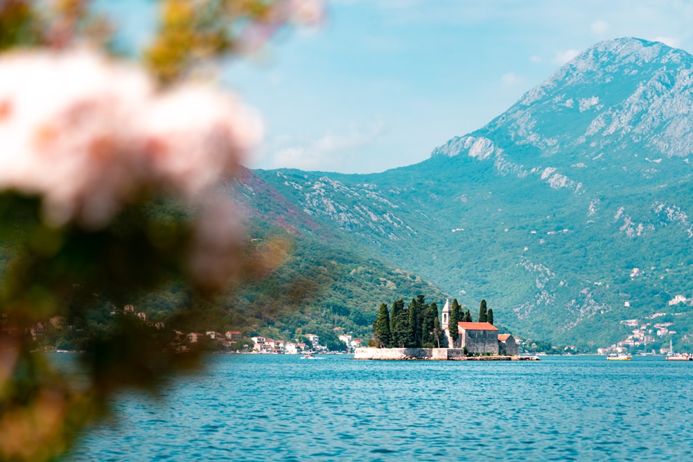 a building on a hill by a body of water with mountains in the background