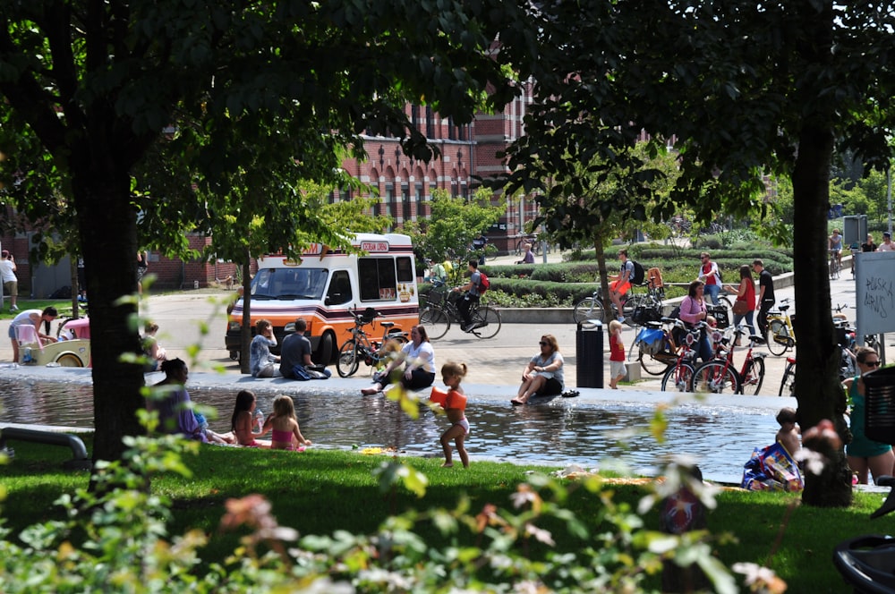 a group of people sitting around a fountain in a park