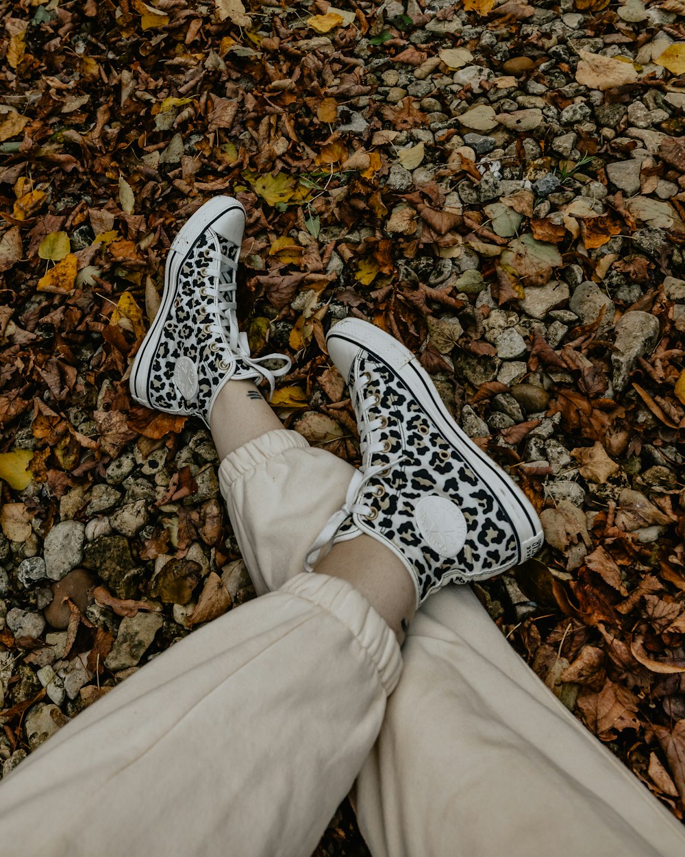 a person's feet in white sneakers on a rocky surface